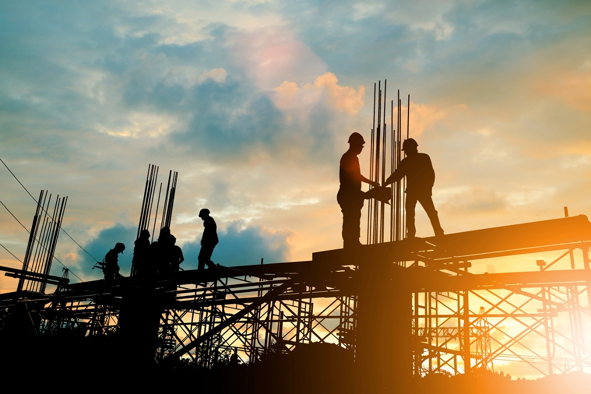 Construction workers on scaffolding silhouetted at sunset